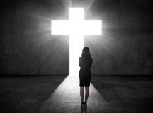 Business woman looking the shining cross on the wall