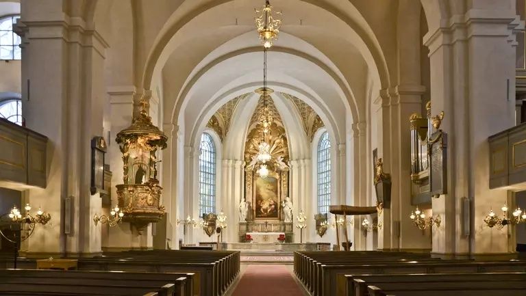 Interiör av en rikt dekorerad kyrka med bänkar och altare